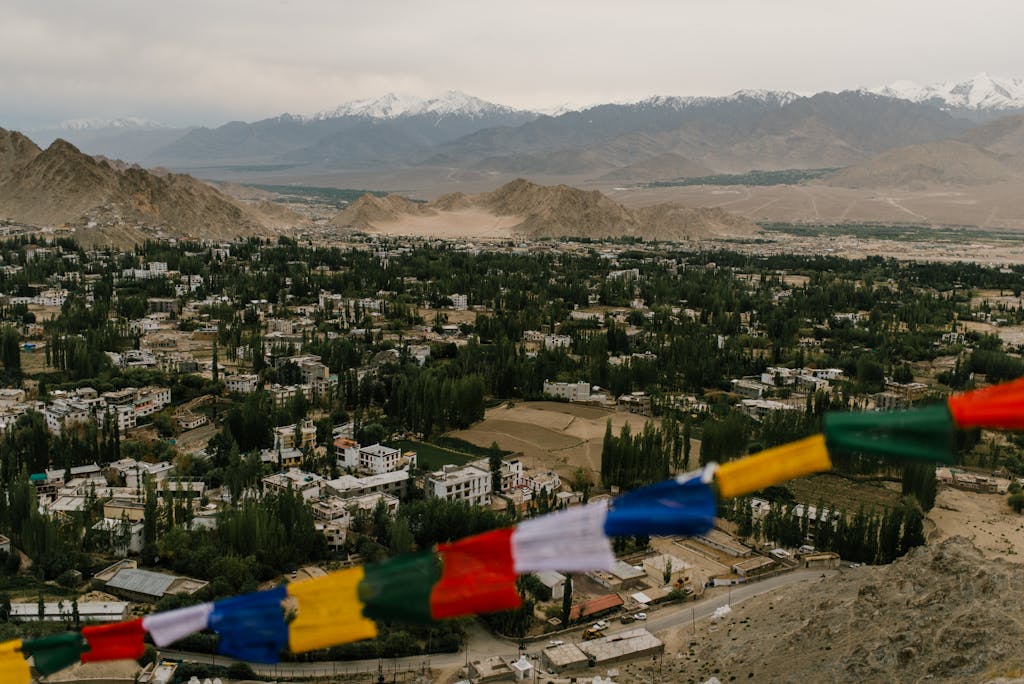 A breathtaking aerial view of Leh, India with vibrant prayer flags and majestic mountain backdrop.