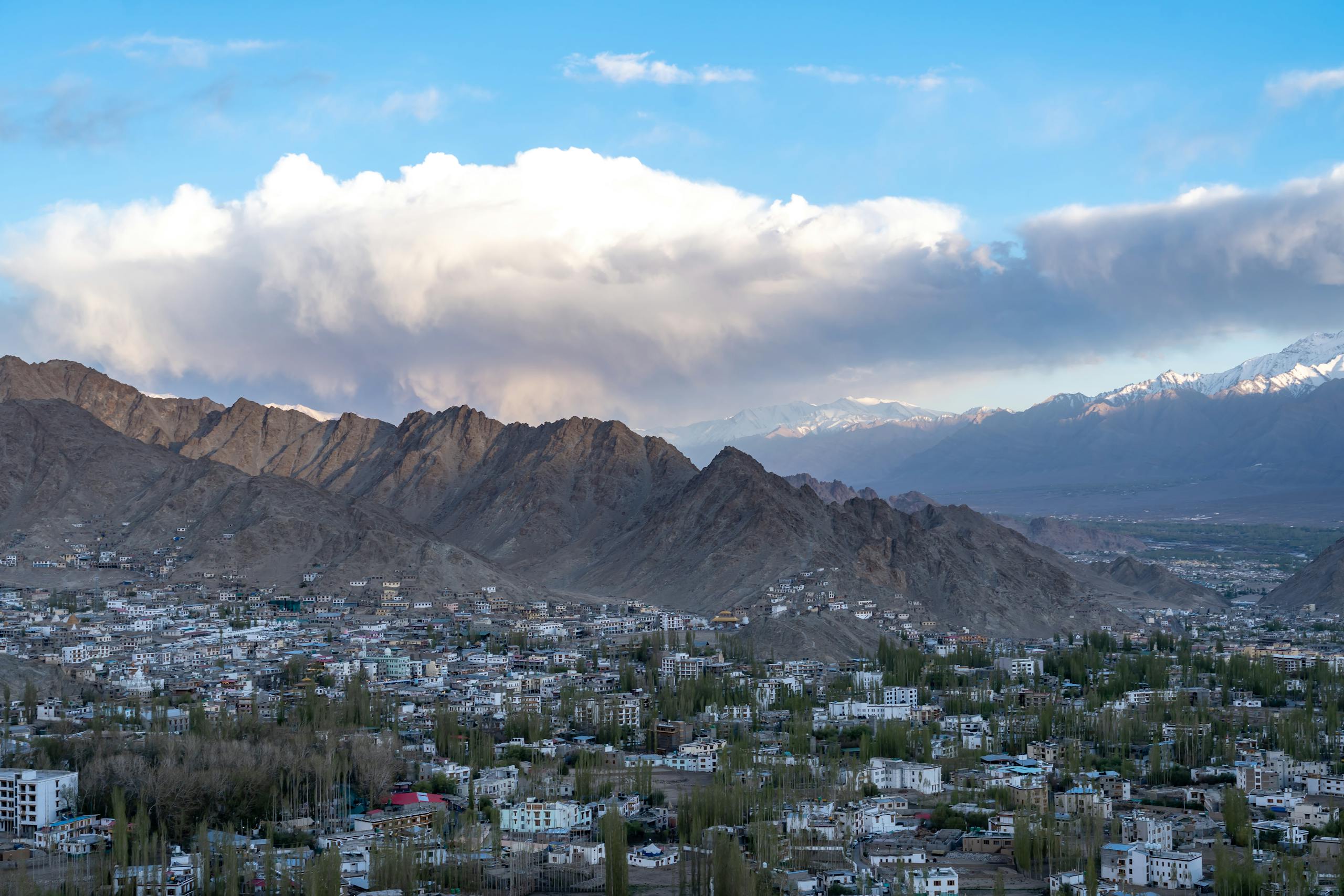 Breathtaking view of Leh town surrounded by towering mountains and clear blue skies.