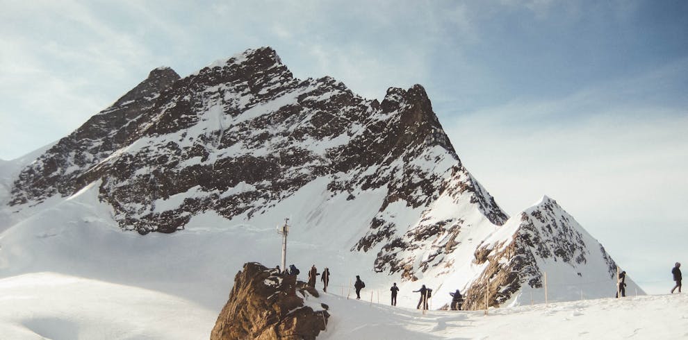 Group of hikers trekking across a snowy mountain range under a clear sky, capturing the essence of adventure.