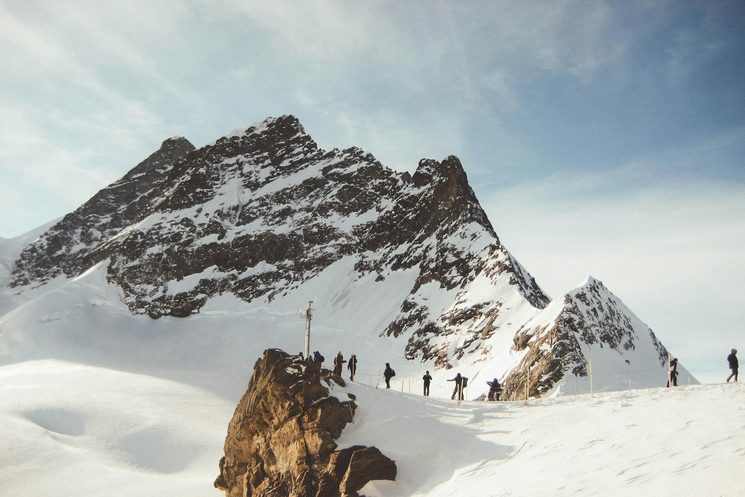 Group of hikers trekking across a snowy mountain range under a clear sky, capturing the essence of adventure.