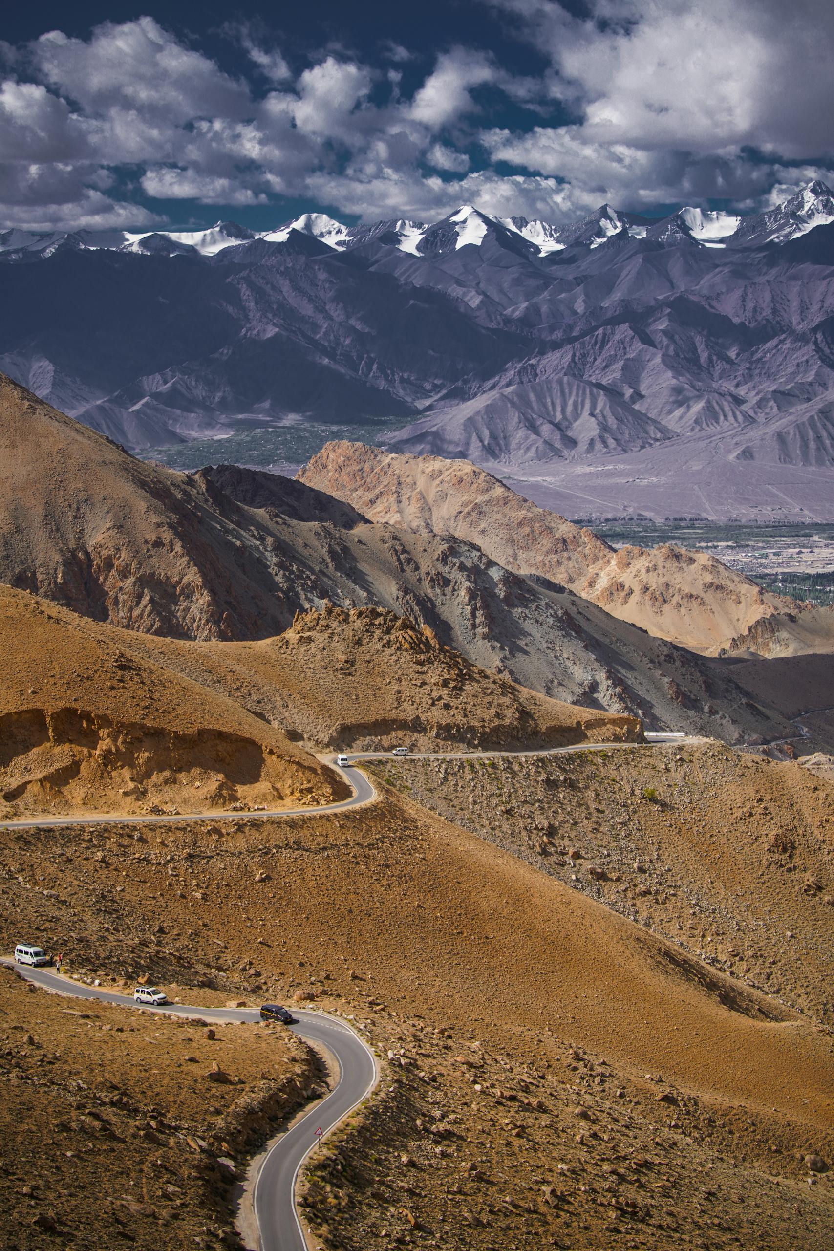 Winding road through majestic mountains in Ladakh, India, under a clear sky.
